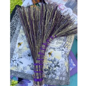 Handcrafted lavender whisk made from dried lavender stems and broom corn, shaped as a turkey wing, wrapped in purple ribbon.