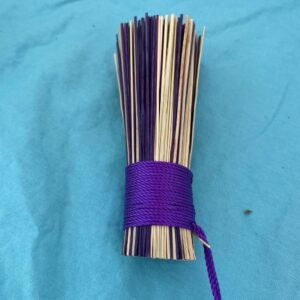 Handcrafted broom corn pot scrubber bound with vibrant purple twine.
