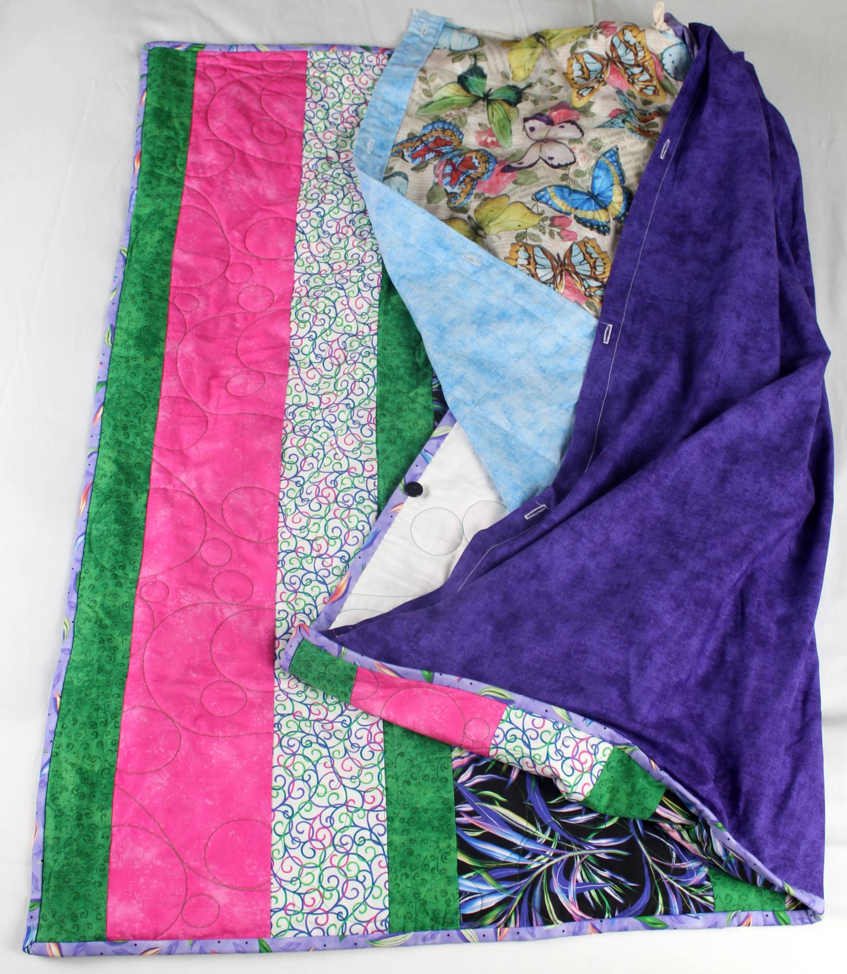 Kaleidoscope quilt with tonal purple backing folded back to reveal the butterfly and rose print insert underneath