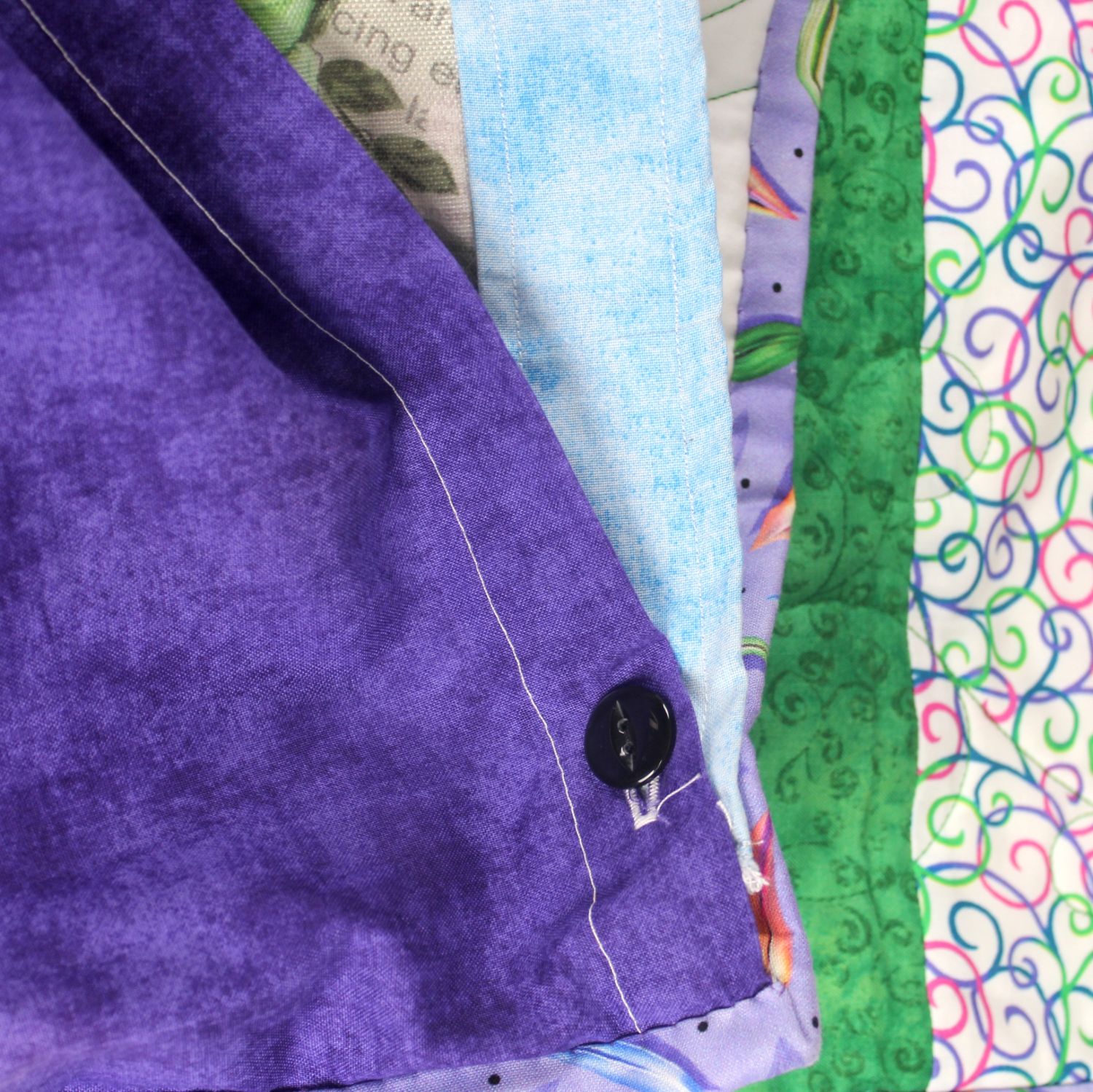 Button-closure opening on the tonal purple backing of the Kaleidoscope quilt, used to access the removable weighted insert