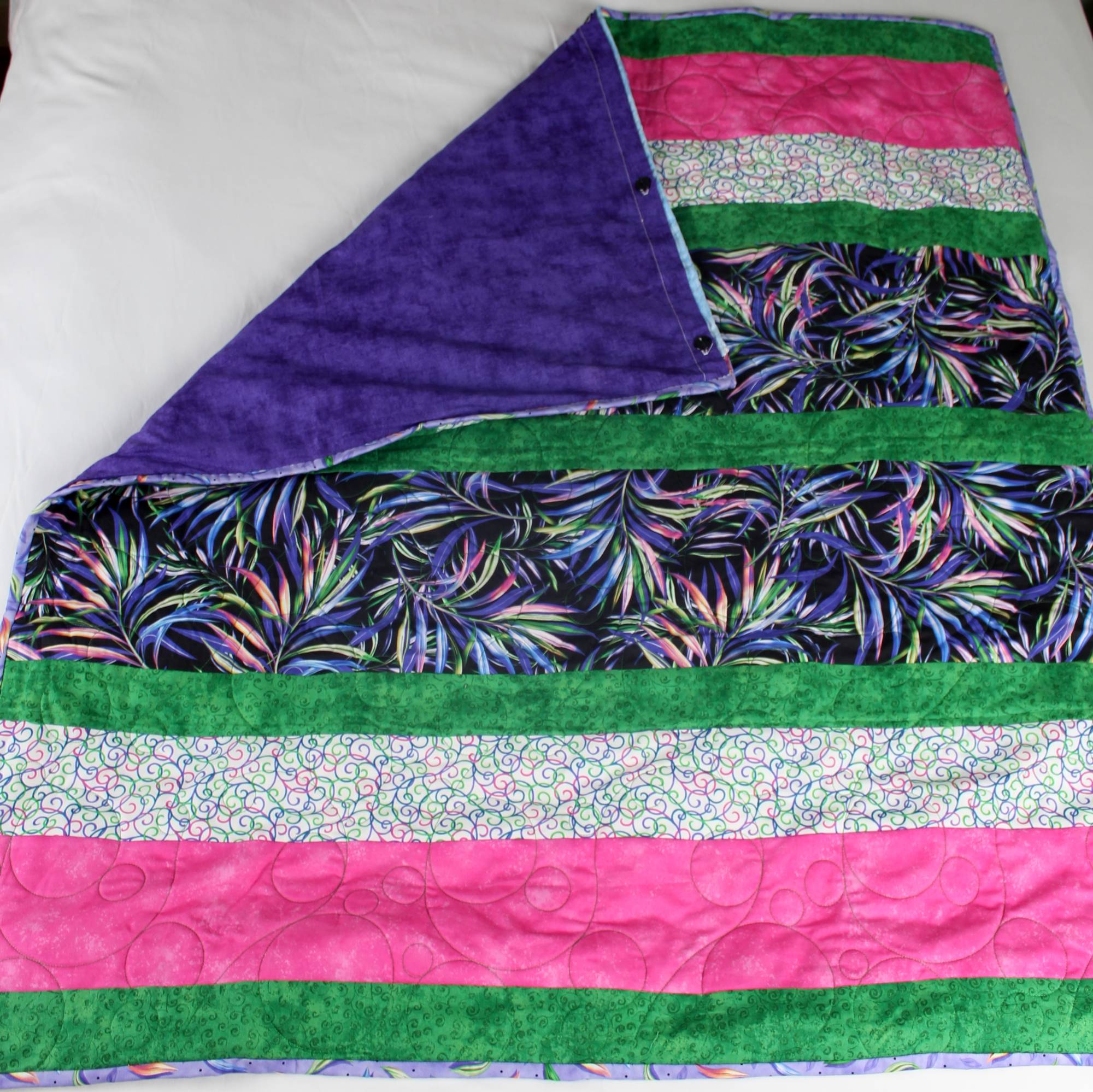 Kaleidoscope handmade lavender weighted quilt, strip-pieced patchwork in hot pink, emerald green, and multicolor swirl print