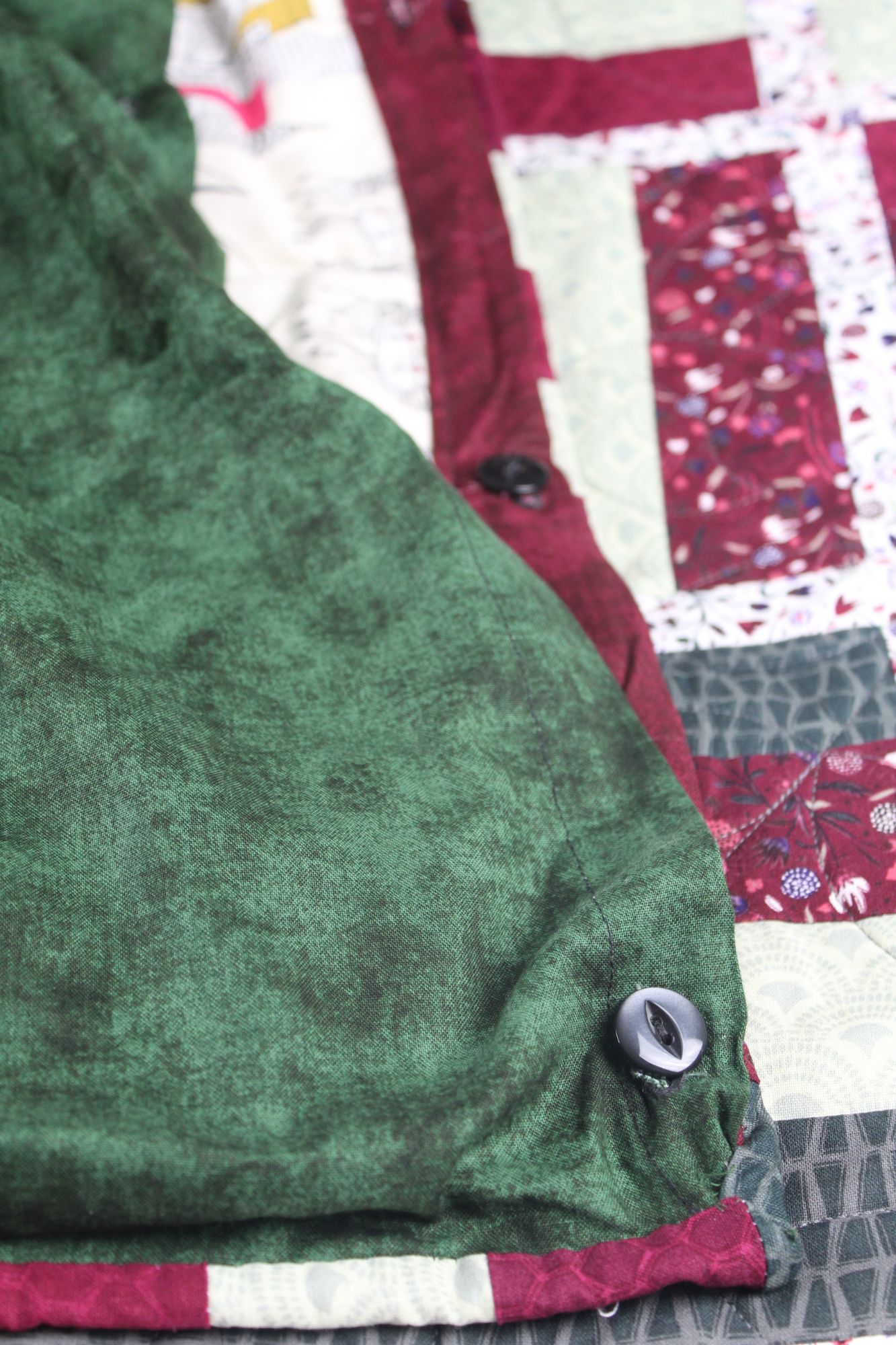 Button-closure opening on the green backing of the Midtown and Mayfair quilt, used to access the removable weighted insert